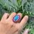 This handmade cocktail ring features a 9.1-carat oval cabochon turquoise and rubies, set in 14k yellow gold. The center...