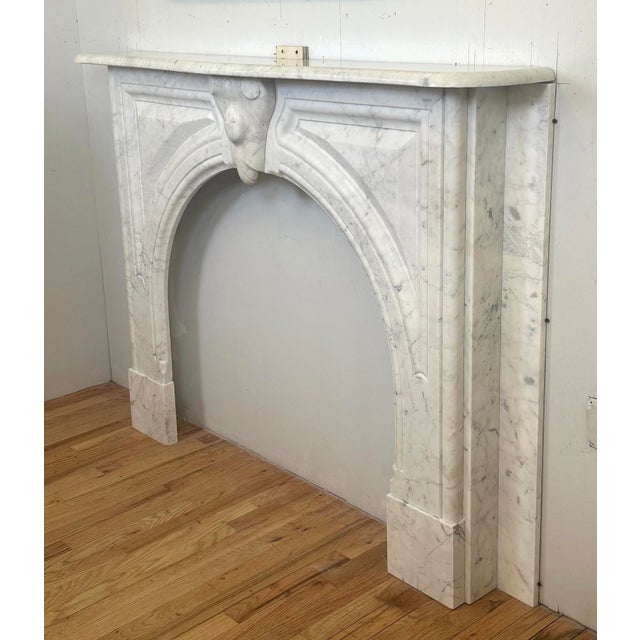 Antique Neoclassical style mantel made of white marble with gray veining. Symmetrical architectural style details add...