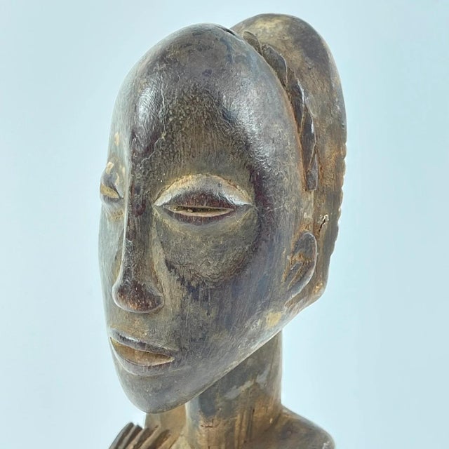 The Luba female figure is crafted as a veneration of feminine beauty and motherhood. Crafted from wood, the Luba female...