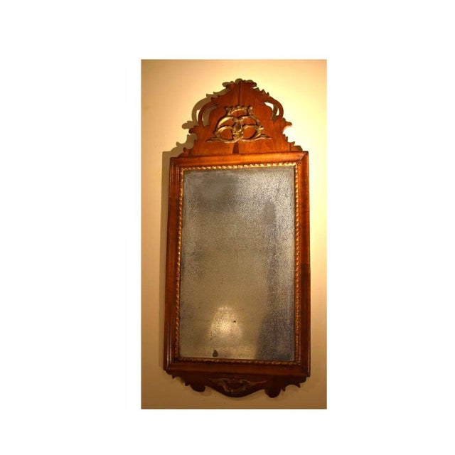 A Rococo influenced looking glass with original mirrored glass still intact, circa 1750. The leafage scroll crest and...