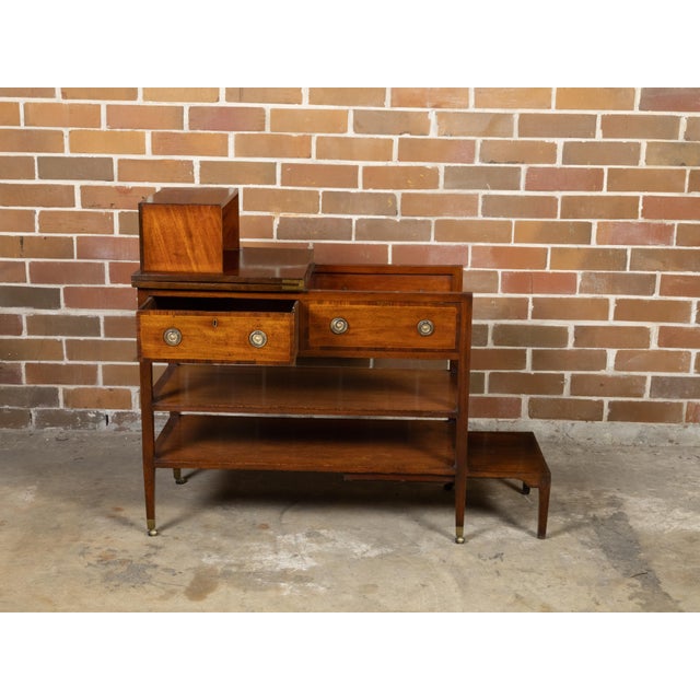 An English metamorphic table on casters from the 19th century with flip top, two drawers, cross banding, two shelves and...