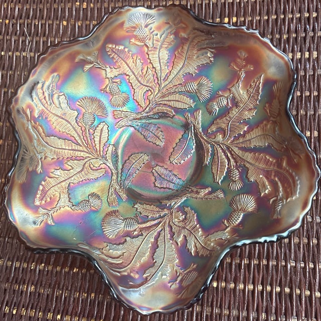 This is a Fenton "Thistle" carnival glass ruffled bowl in amethyst, featuring an iridescent finish produced by the Fenton...