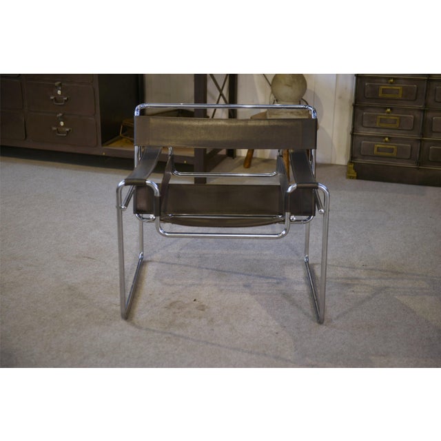 A modernist icon consisting of a curved, chromed tubular steel frame and black leather straps (backrest, seat, and...