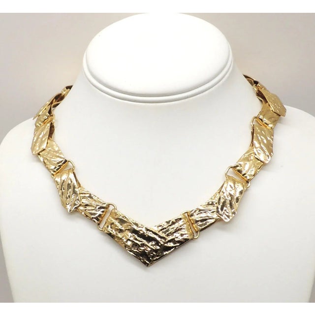 This is part of Chairish’s Costume Jewelry assortment. 1970s Modernist goldtone rough look v center link necklace with...