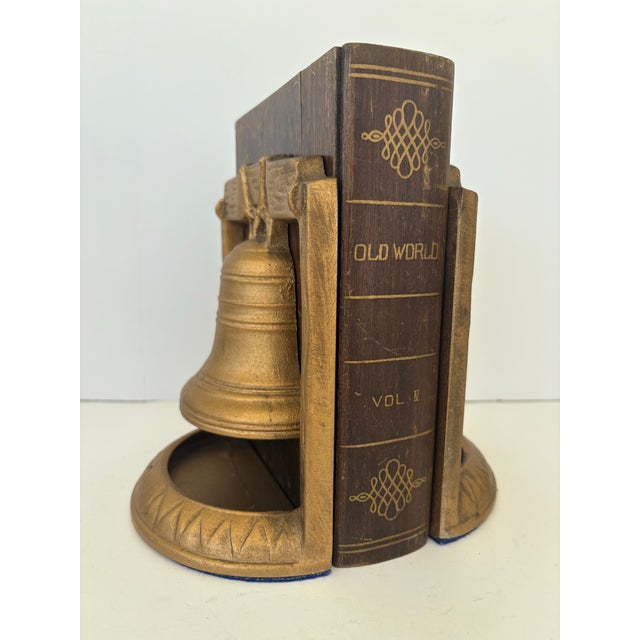 This striking pair of vintage bookends features a sculptural liberty bell motif rendered in solid cast metal with a warm...