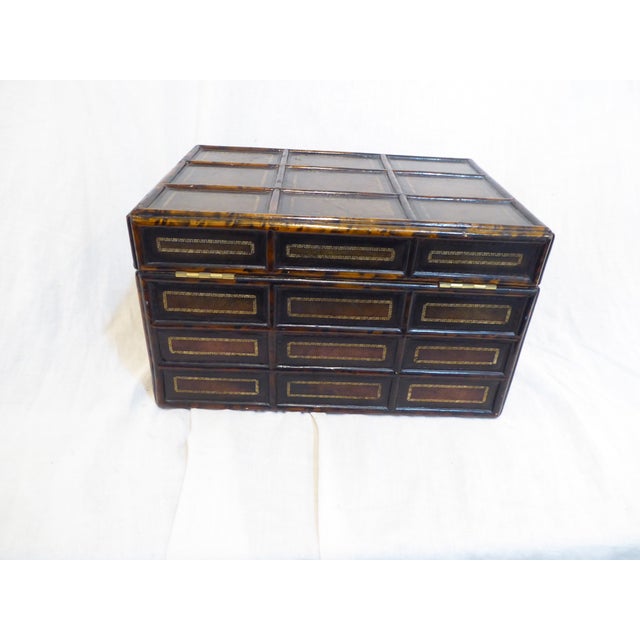 This leather box, impressed with gold-leaf, trimmed in bamboo is lined with paper.