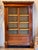 A mahogany bibliothèque with a single glazed door, interior shelves, pilaster sides with bronze mounts, and a black marble...
