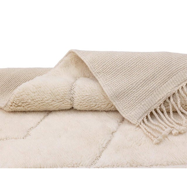 Two quiet patterns, one serene field: diamonds and lines meeting in soft ivory. A soft ivory field covers the rug,...