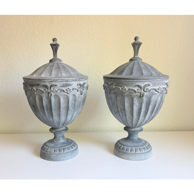 A matching pair of large, antique lead metal lidded garden urns modeled in an English Neoclassical or Adam style...