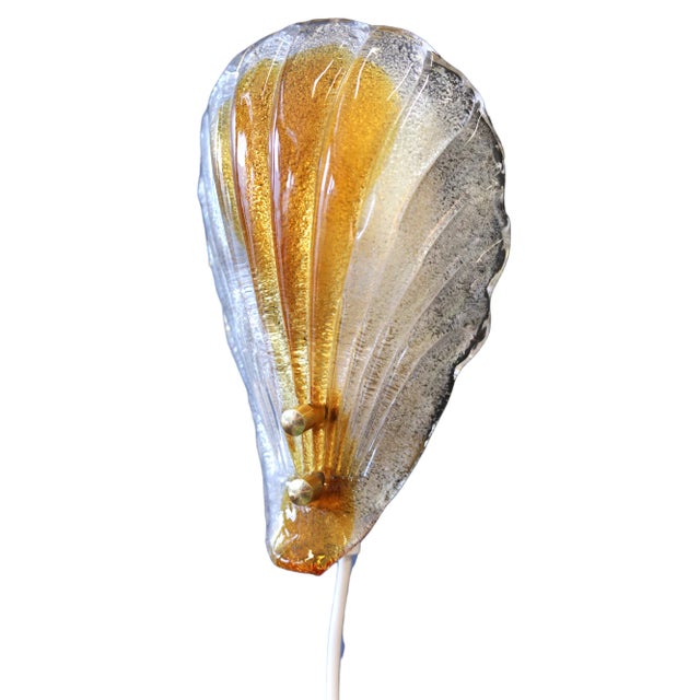 Wonderful shell-shaped wall lamp with heavy glass shade and brass lamp holder. Manufacturer is Fåglaviks Glasbruk. The...