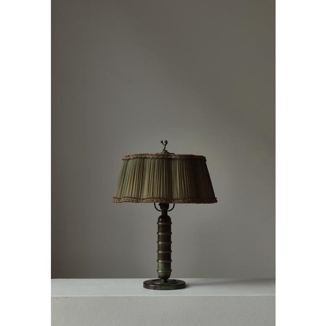 A refined Swedish Art Deco table lamp from the 1930s, crafted in bronze with a beautifully aged green patina. The elegant...