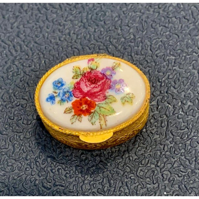 Cute Italian trinket box from the 70s with a porcelain topped lid depicting a floral bouquet of red, pink, blue and purple...