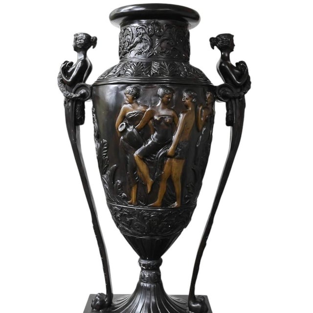 This Tall Black Metal Urn with Pedestal is an impressive decorative piece featuring intricate sculptural detailing and...