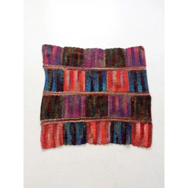 This vintage knit throw blanket bursts with rich color and texture, featuring bold stripes of red, purple, blue, and green...