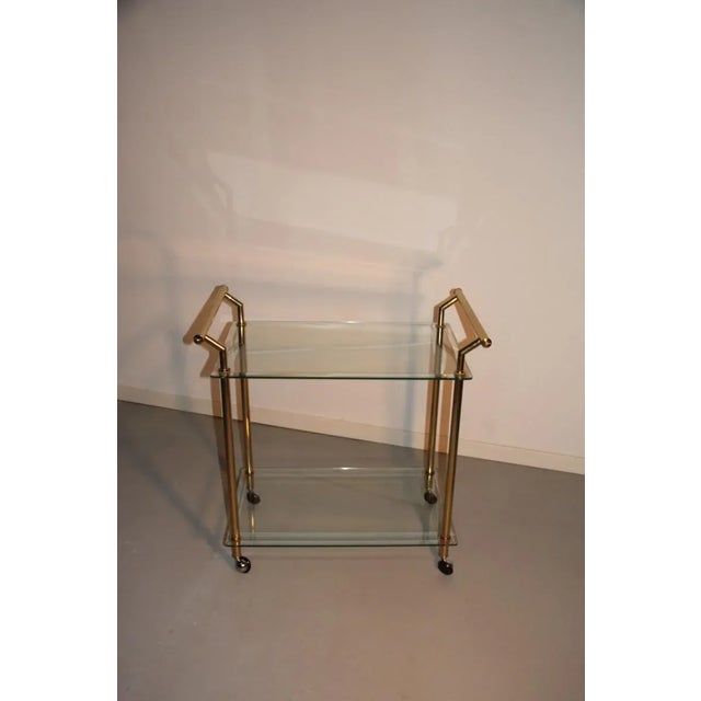 This bar cart originates from the 1970s and is made from gold brass with cut glass trays.