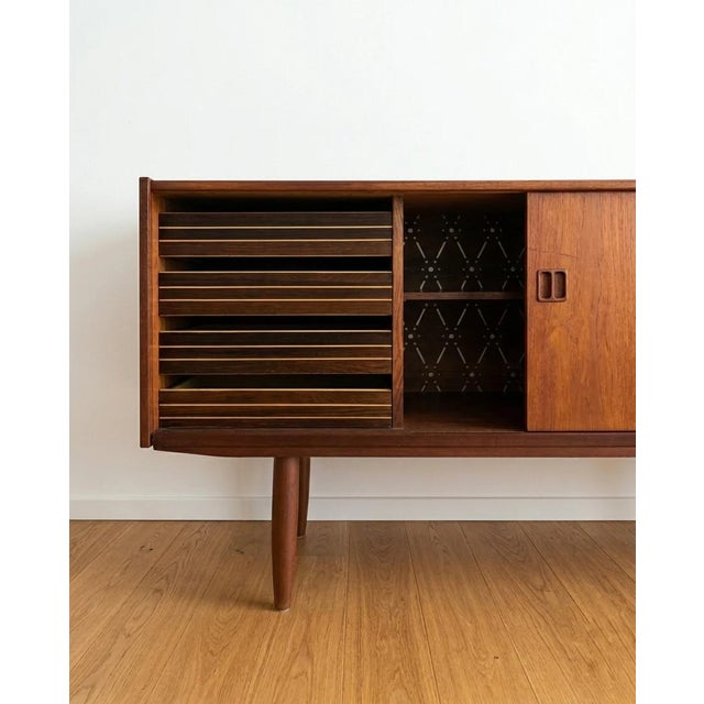 Danish teak sideboard from the 1950s, 200 cm. Two large sliding doors with recessed vertical handles sit on tapered legs....