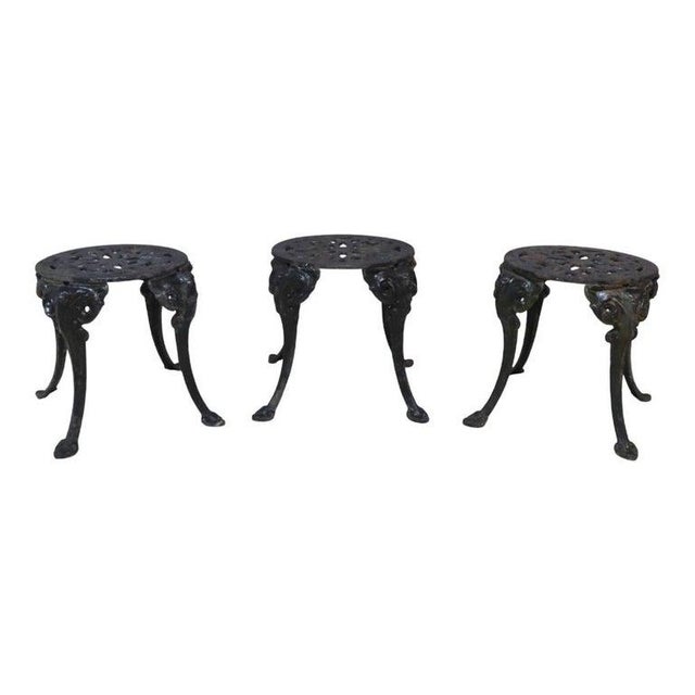 This offering presents a set of three antique cast iron garden side tables or stools, dating to approximately 1920. Each...