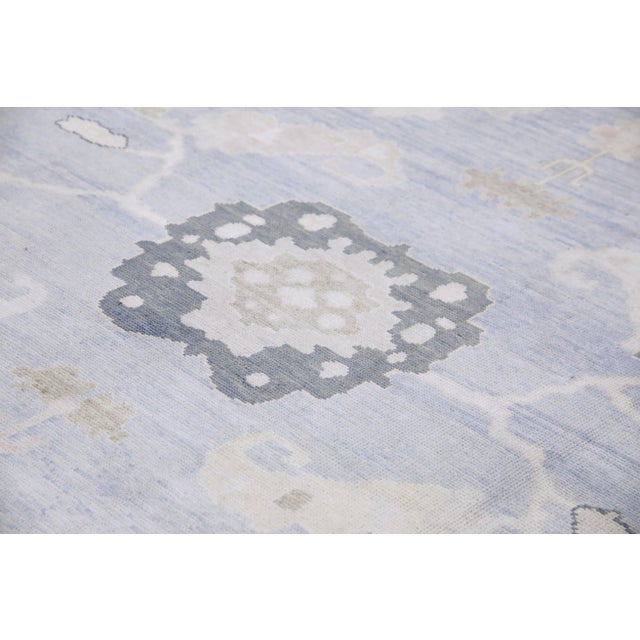 This modern Turkish Oushak rug is a stunning piece of art that has been handwoven using traditional techniques by skilled...