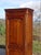 A bonnetière (wardrobe) crafted entirely from solid cherry wood, traditionally made in France in the 1980s. This tall,...