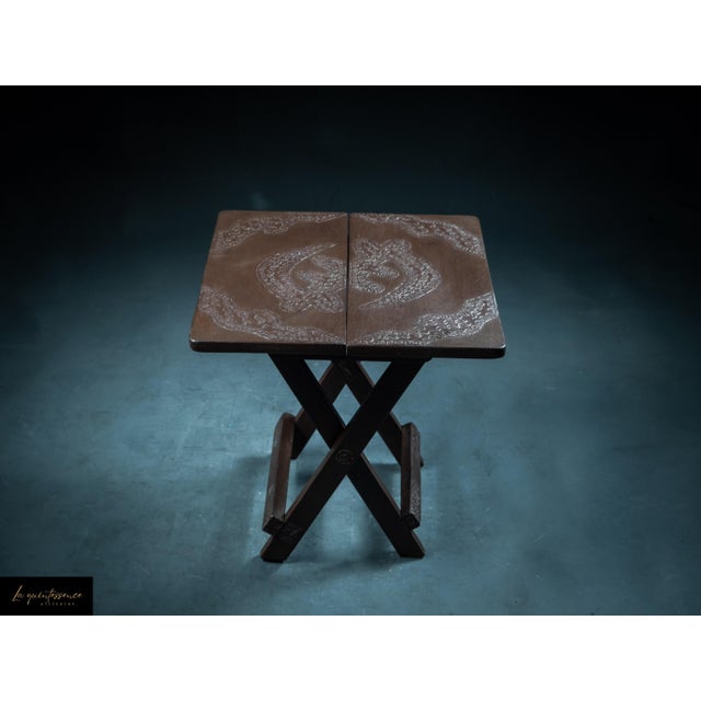 This elegant folding table embodies Ghana's artisanal heritage through its harmonious blend of wood and finely engraved...
