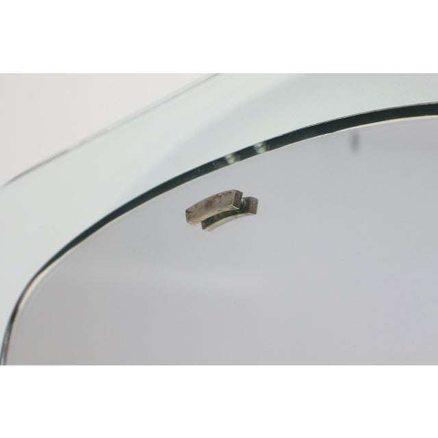 Thick curved glass mirror with mirror and wall mounting plate. Made by Fontana Arte, Milan, Italy. The back has a paper...