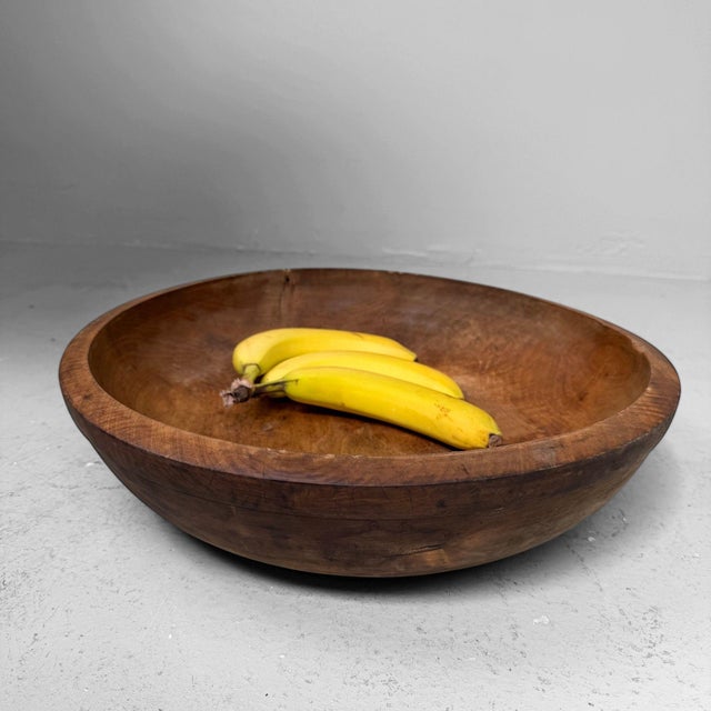 A beautiful Japanese wooden dough bowl, hand-carved from solid wood, with a warm natural tone, deep rounded form and...