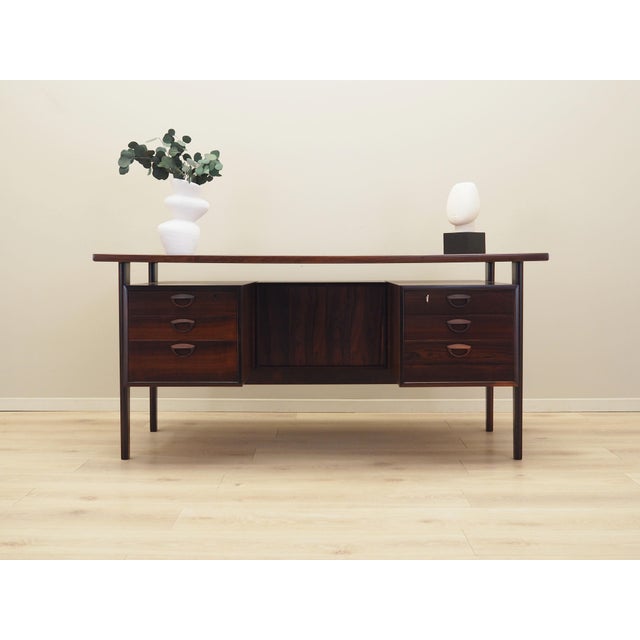 The desk was made in the 1970s. The structure and the top are covered with rosewood veneer. The legs are made of solid...