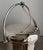 Vintage silver-plate ice bucket with a clean cylindrical form and sculptural swing handle detail. The curved support arm...