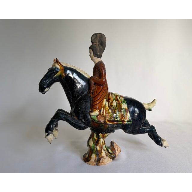 A striking matched pair of Chinese Tang-style pottery figures depicting two riders on spirited galloping horses. Each...