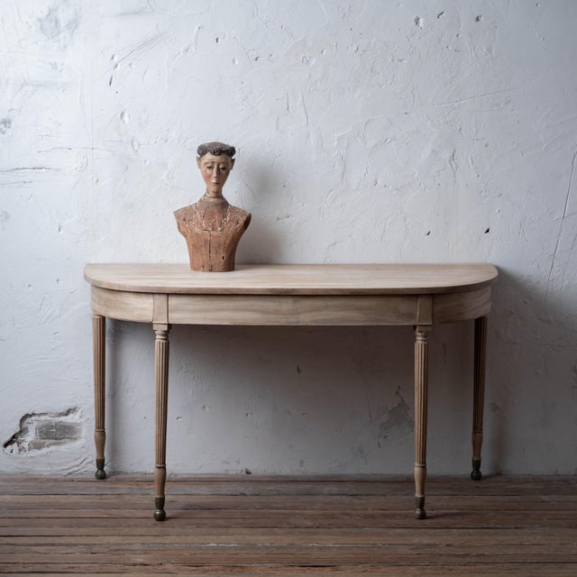 A Regency mahogany demi-lune console table, circa 1815. The rounded demi-lune top raised on four tapering fluted legs...