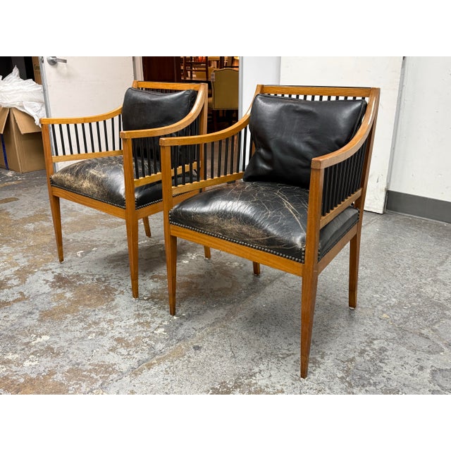 Design Plus Gallery presents a Pair of Circa 1835 Austrian Biedermeier Cherry Wood + Leather Arm Chairs. The chairs...