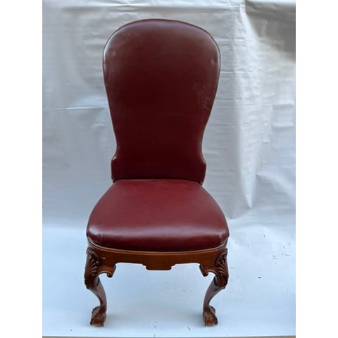 A single carved wood side chair featuring ball and claw feet and dark red leather upholstery with nailhead trim.