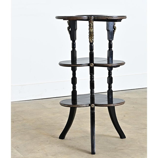 A French ebonized étagère from the 1870s, combining practical storage with refined decorative detailing. The three-tier...