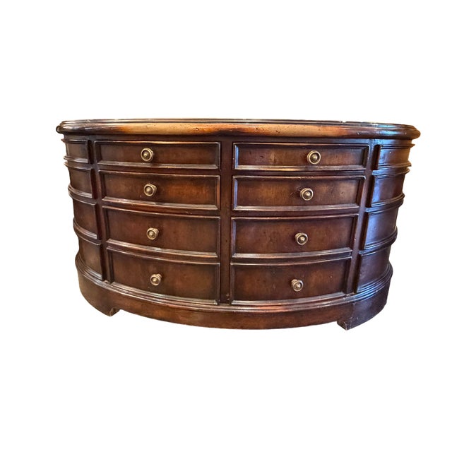 Oval wood coffee table featuring a dark finish and a total of 12 drawers—arranged in 6 pairs across both sides—fitted with...