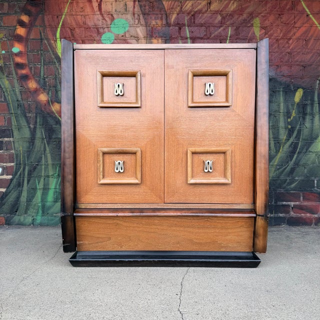 This is a beautiful tall boy dresser by Hellum Furniture Company in the style of James Mont. It features two large doors...