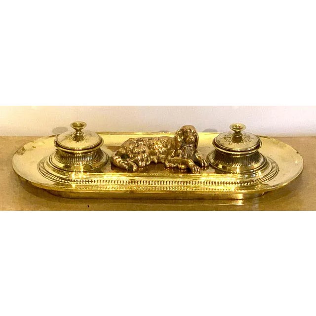 19th century English brass resting dog double inkwell, the wells opening to the left and the right.