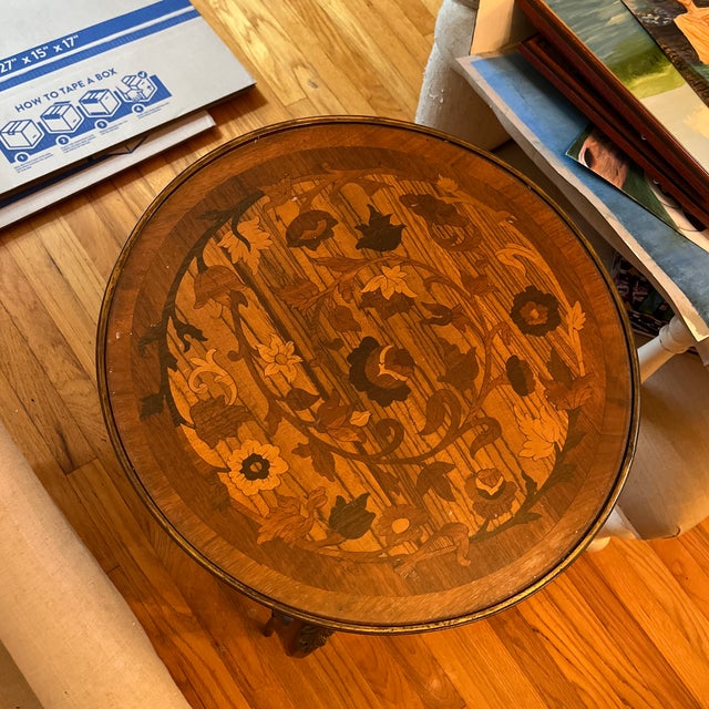 Louis XV style table made from wood with feathered brass accents. Glass covers intricate design on top of table to protect...