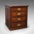 This is an antique campaign chest of drawers. An English, pitch pine shop retail cabinet, dating to the Victorian period,...