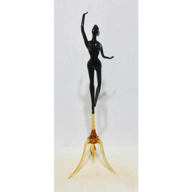 Fine Studio glass figure, Murano pipework dancer of a female nude, poised on top of a tripod base. Black body and amber...