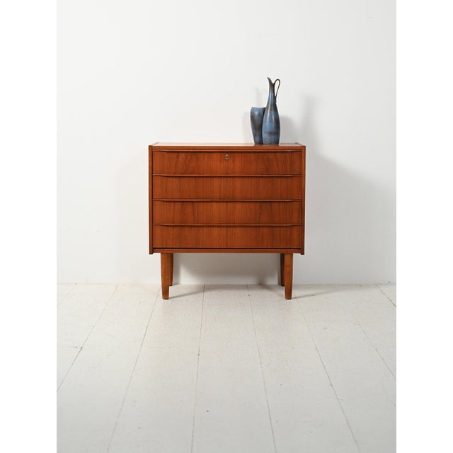 1960s Nordic teak chest of drawers with carved handles, slender turned legs, and a warm, enveloping grain. This 1960s...