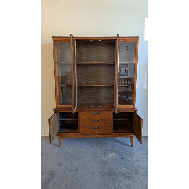 DESCRIPTION: A classic mid century modern hutch by Garrison Furniture Co. featuring a clean walnut profile, glass display...