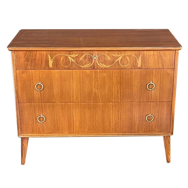 the rectangular top above a frieze drawer inlaid with elegant scrolling rinceau centering a lined keyhole, over two long...