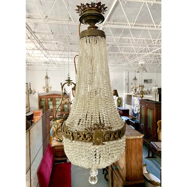 French crystal and brass chandelier circa 1920. Strings of crystal beads hang from a brass canopy crowned with a pierced...