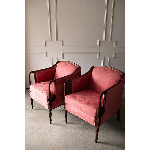 A striking pair of 20th-Century French inspired bergère chairs by Woodmark Originals upholstered in a rich pink damask....