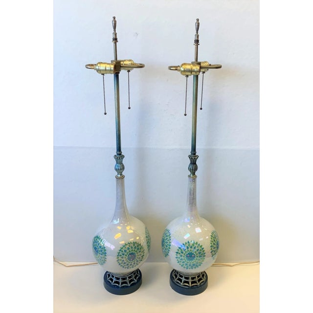 A groovy pair of mid-century modern glass lamps reverse painted with a blue and green retro design. They feature double...