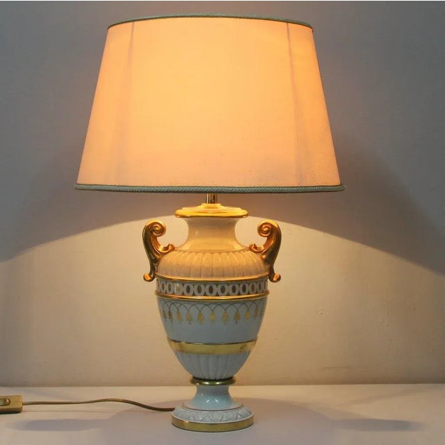 This lamp was designed in the 1970s and produced in Italy. It is made from porcelain and features golden details with...