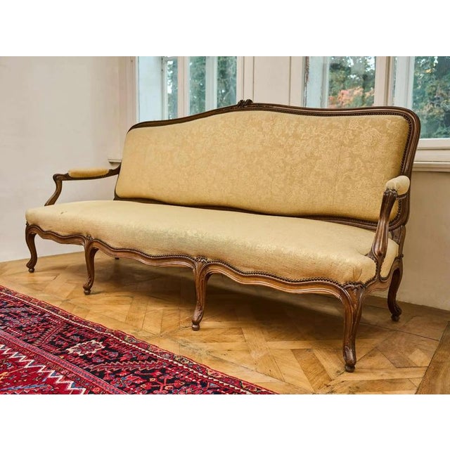 Large and sturdy sofa in the Louis XV rococo style. The sofa is subtly decorated with fine carving, profiles and curved...