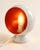A striking vintage Space Age table lamp with a sculptural rounded form, glossy white exterior and bold red-orange...