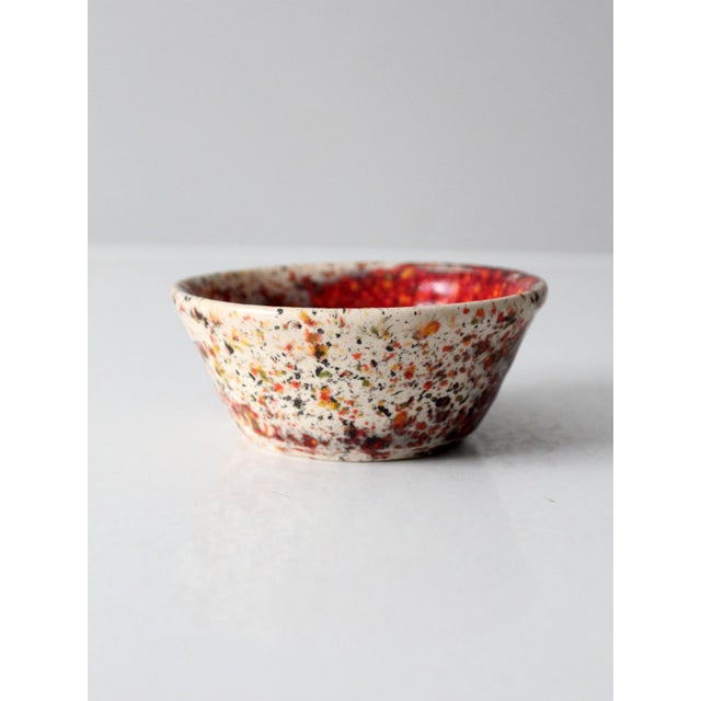 A vintage handmade studio pottery bowl featuring a richly layered glaze in vivid red with expressive speckling over a...