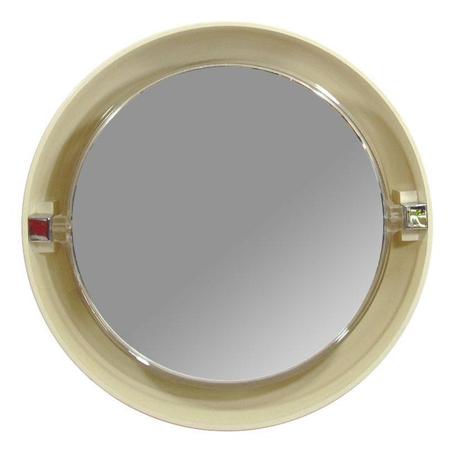 A striking wall mirror with an illuminated frame. It dates from the 1970s and is made of light cream-colored plastic. The...